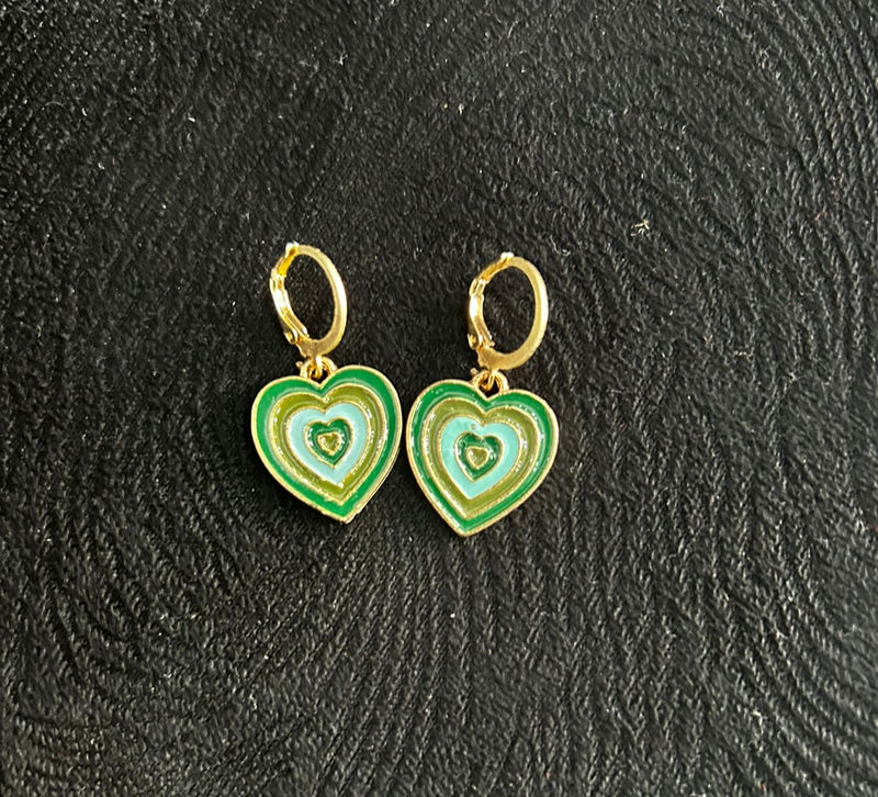 Heart-shaped earrings with green and gold design on a textured black background