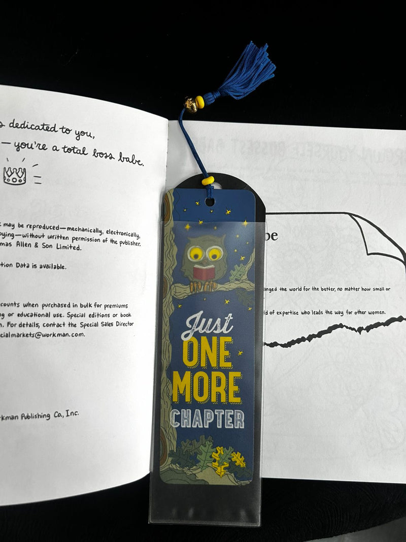 Bookmark with a cartoon character and text 'Just One More Chapter' on an open book.