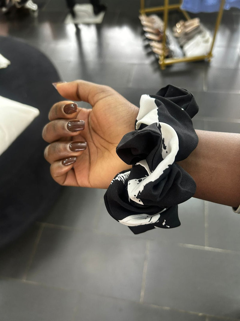 Hand holding a black and white scrunchie 